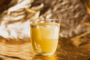 A bright yellow cocktail with ice in a rocks lowball glass