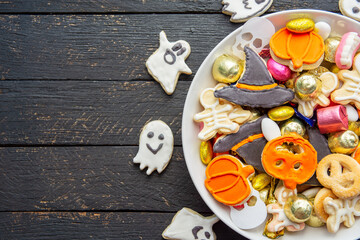 Halloween Jack o Lantern candy bowl with candy and halloween cookies Trick or Treat on black wooden background