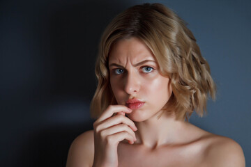 Closeup pretty portrait an angry discontented woman with finger on lips against dark background. Female emotion happy and actress show. Concept of satisfaction and inspiration. Copyright space