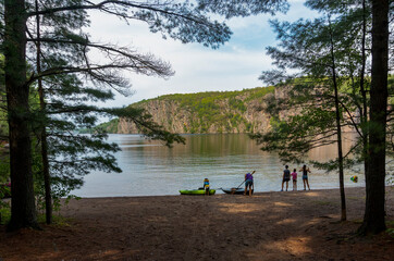 The boy brought a paddle and is waiting for his grandfather near the kayak