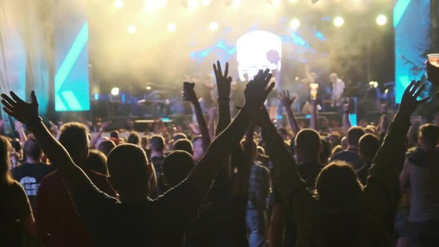 Crowd of Fans at Live Rock Concert Raise Hands and Dance. Slow Motion 240 fps