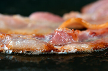 Obraz na płótnie Canvas Macro view of bacon slice in frying pan.