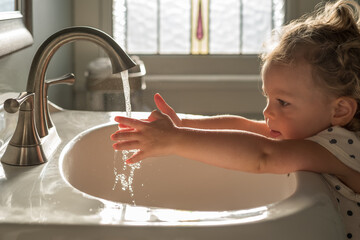 Cute little toddler girl washing her hands