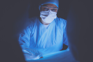 Doctors team in surgery in a dark background.