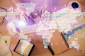 Double exposure of man's hands typing over computer keyboard and business theme hologram drawing. Top view. Financial markets concept.