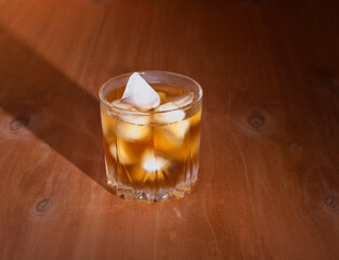 misted glass of whiskey with sharp shadow on wooden background
