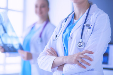 Close up shoot of doctor's crossed hands and colleague with x-ray on the background.