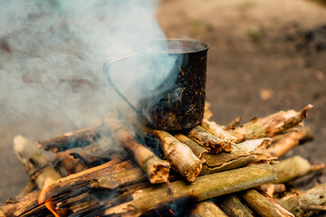 metal mug on the background of fire, picnic with fire in the forest