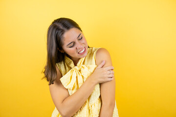 Young beautiful woman over isolated yellow background with pain on her shoulder and a painful expression