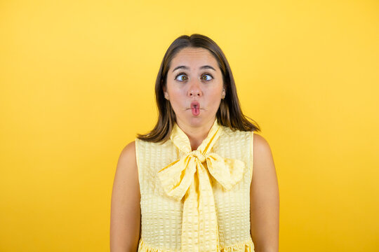 Young beautiful woman over isolated yellow background making fish face with lips, crazy and comical gesture.