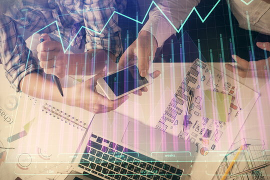 Double exposure of forex graph drawing and man and woman working together holding and using a mobile device. Trade concept.