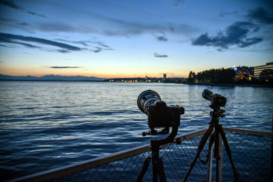 DSLR cameras on tripod taking photos of sunset over the sea. 