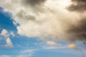 Sunlight and rain clouds are moving under the blue sky.