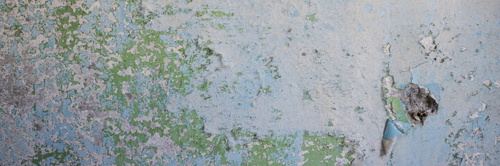 Peeling paint on the wall. Panorama of a concrete wall with old cracked flaking paint. Weathered rough painted surface with patterns of cracks and peeling. Panoramic texture for background and design.