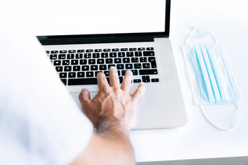 Person working online with a laptop in times of covid 19 coronavirus. Telecommuting, working from home.