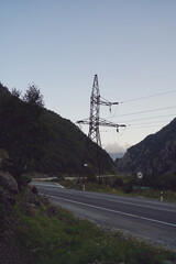 High voltage electric transmission tower in mountainous area. Object of electric power line in mountains in evening.