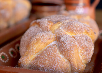 Exquisite pan de muerto or bread of dead with sugar on traditional mud dishes.