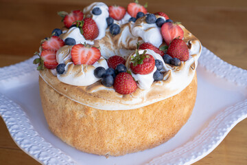 Delicious red fruit bread with whipped cream on top on a white plate.