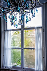 Vintage blue and clear crystal chandelier against a vintage window.