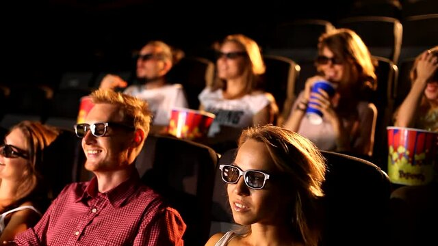 A group of excited young attractive happy male female friends enjoying 3d 4d action movie theater cinema eating popcorn