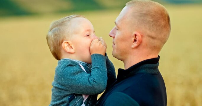 Portrait of dad with his son, they look at each other and smile, the son plays with dad. Young dad is happy to be with his son together, joyful fatherhood. Happy childhood with dad. 4k, ProRes