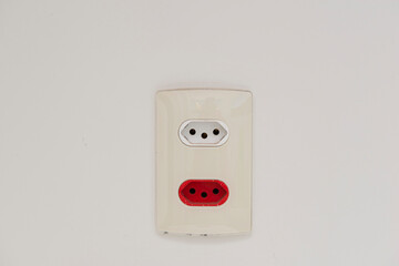 Close Up shot of a white wall plug with a Swiss and Brazilian standard socket.