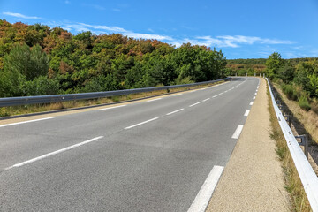 Fototapeta na wymiar Regional road, with double lane and shoulder, crossing small forest, Provence-Alpes-Côte d'Azur region, Var, France