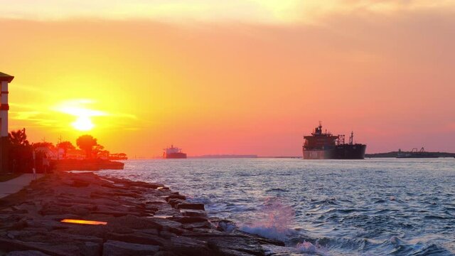 Beautiful sunset at Port Aransas, Texas with oil tankers on the water of the ship channesl from Corpus Christi waves along the shore.