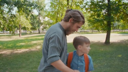Slowmo shot of bearded father hugging cute schoolboy after taking him to school on sunny morning