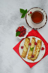 Delicious homemade pancakes with raspberries and a cup of tea top view flat lay with copy space for text and design. Concept of celebrating the Maslenitsa holiday.