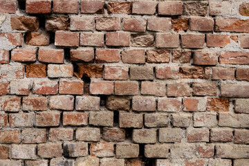 Old cracked and damaged red brick wall. Background of an old brick house texture.