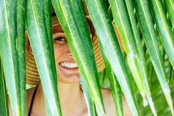 Woman hiding behind the palm leaves. Vacation concept