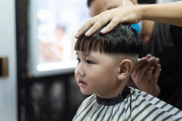 little boy hair with an electric clipper, in barber shop