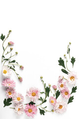 Obraz na płótnie Canvas flower frame layout. beautiful pink chrysanthemums and green leaves on a white background. flat lay, vertical frame, copy space