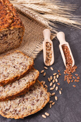 Loaf of wholegrain bread for breakfast, ingredients for baking and ears of rye or wheat grain