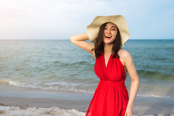Obraz na płótnie Canvas cheerful woman in red dress enjoying on sea beach