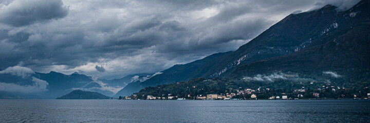 Fototapeta na wymiar Landscape of dark lake Como with very cloudy sky and mountains, which is located in Northern Italy.