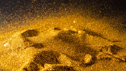 Sprinkle glitter gold dust on a black background with copy space