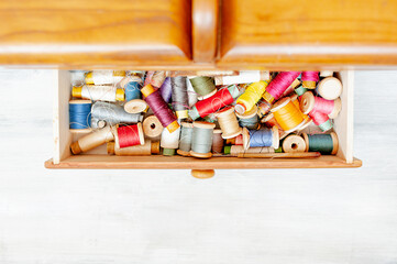 Obraz na płótnie Canvas lots of colorful balls of thread in wooden box, tools for sewing hobby, top view