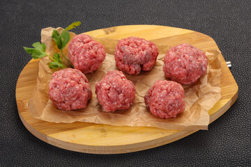 Raw meatball over wooden background