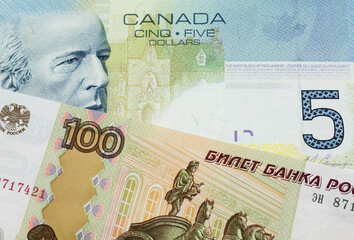 A macro image of a Russian one hundred ruble note paired up with a blue five dollar bill from Canada.  Shot close up in macro.
