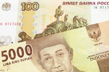 A macro image of a Russian one hundred ruble note paired up with a orange five thousand Indonesian rupiah note.  Shot close up in macro.