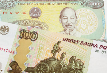 A macro image of a Russian one hundred ruble note paired up with a yellow one thousand dong bill from Vietnam.  Shot close up in macro.