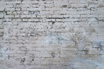 The texture of the old brick wall painted white with peeling paint