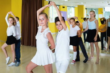 Diligent friendly smiling positive boys and girls having dancing class in classroom