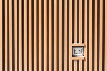 Plug socket on light brown wooden wall pattern at outdoor installation