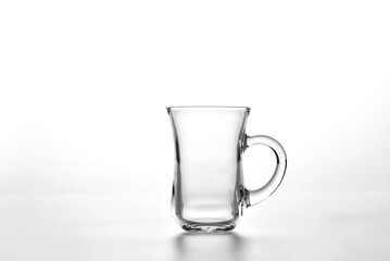 Empty glass cup for Turkish tea (armudu) with a handle on a white background.