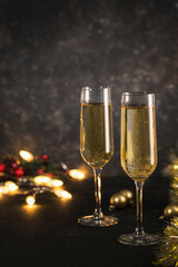New year 2021 - two glasses of champagne on a dark background with bokeh from garlands.