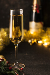 New year 2021-a glass of champagne on a dark background with a bokeh of garlands.