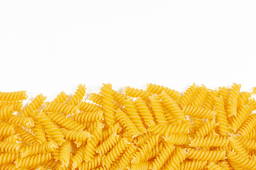 Uncooked fusilli pasta noodles on white background. Italian pasta border for menu design template, fusilli over white background with copy space